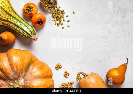 Herbstlicher Hintergrund mit Kürbissen, Birnen, Walnüssen, Kürbiskernen, Kaki und Kopierraum Stockfoto