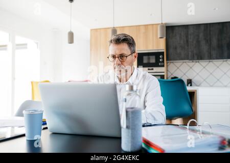 Ein ernsthafter Geschäftsmann, der im Heimbüro am Laptop arbeitet Stockfoto