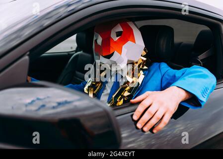 Lustige Figur trägt Tiermaske und blauen Business-Anzug im Auto Stockfoto