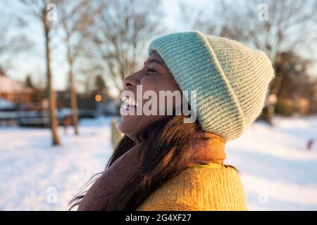 Frau mit blauem Strickhut und Schal lacht im Winter Stockfoto