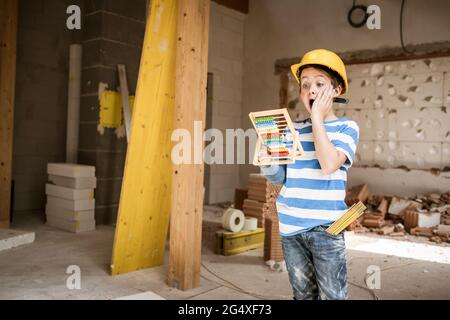 Überrascht Junge hält Abacus Spielzeug während des Wiederaufbaus Haus Stockfoto