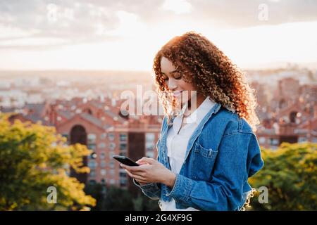 Junge Frau SMS auf Handy in der Stadt Stockfoto