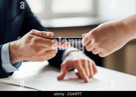 Männlicher Unternehmer, der einem Kollegen im Amt den Stift gibt Stockfoto