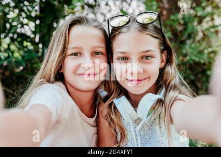 Lächelnde Mädchen, die im Garten Selfie machen Stockfoto