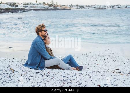 Mittelerwachsenes Paar, das sich am Strand entspannt Stockfoto