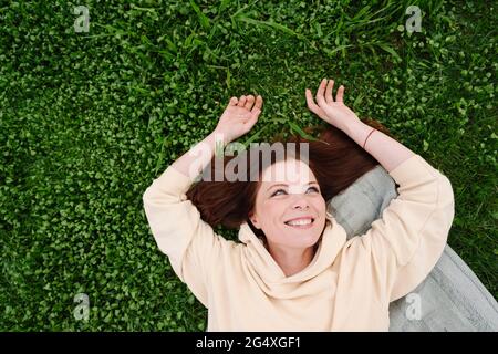 Glückliche, reife Frau, die im öffentlichen Park auf Gras liegt Stockfoto