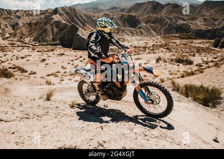 Männliche Biker Reiten Enduro Motorrad auf Wüstenstraße während sonnigen Tages Stockfoto