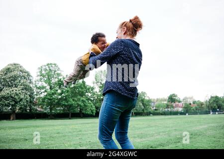 Glückliche Mutter, die mit dem Sohn im Park spielt Stockfoto