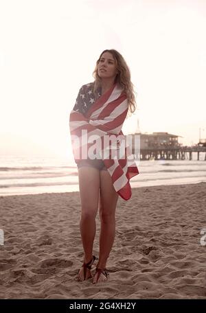 Wunderschöne Frau, die in Flagge gehüllt war, als sie am Strand von Santa Monica stand Stockfoto