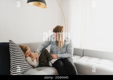 Verspielte Mutter kitzelt Sohn auf Sofa im Wohnzimmer Stockfoto