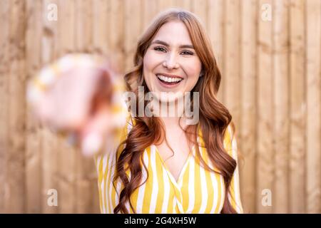 Fröhliche Rothaarige Frau, die gegen eine hölzerne Wand steht Stockfoto