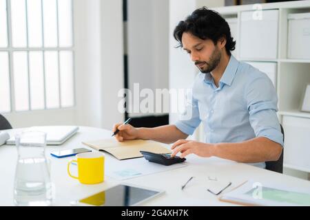 Junge männliche Unternehmer mit Rechner während der Arbeit im Büro Stockfoto