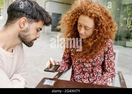 Frau scannt QR-Code auf dem Tisch im Café Stockfoto