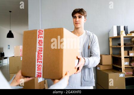 Geschäftsmann liefert Paket an weibliche Kunden im Lager Stockfoto