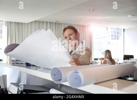 Geschäftsfrau Blick auf Blaupausen in Büro Stockfoto