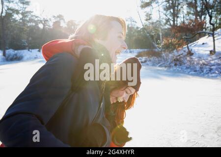 Junges Paar, das während des Winters an einem sonnigen Tag lacht Stockfoto