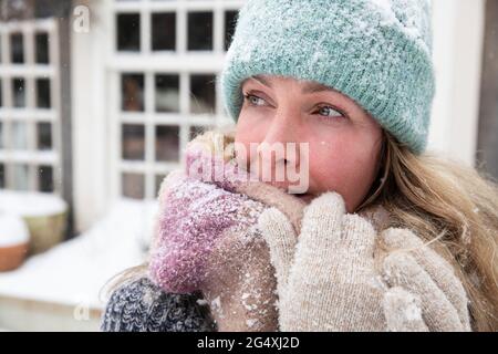 Blonde Frau bedeckt den Mund mit Schal, während sie wegschaut Stockfoto