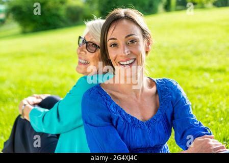 Eine glückliche Frau mittleren Erwachsenen mit einer älteren Frau, die im öffentlichen Park sitzt Stockfoto