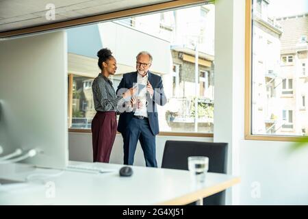 Männliche und weibliche Unternehmer diskutieren über digitale Tablets im Büro Stockfoto