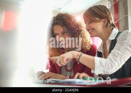 Fröhliche Freiberuflerinnen, die im Café am Laptop arbeiten Stockfoto