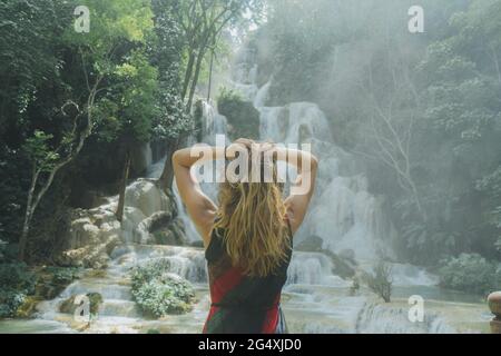 Junge Frau mit der Hand im Haar vor dem Kuang Si Wasserfall in Luang Prabang, Laos Stockfoto