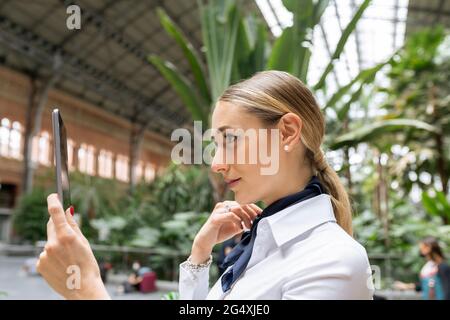 Selbstbewusste weibliche Flugbegleiterin, die im Garten Selfie auf einem digitalen Tablet abnimmt Stockfoto