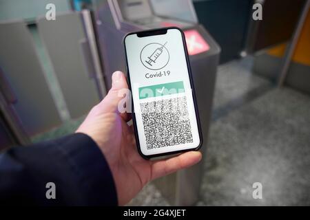 Mann, der am Flughafen einen digitalen COVID-19-Impfpass auf dem Smartphone vorführt Stockfoto