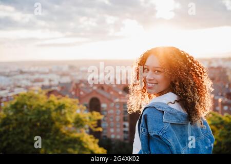 Junge Frau schaut bei Sonnenuntergang über die Schulter Stockfoto