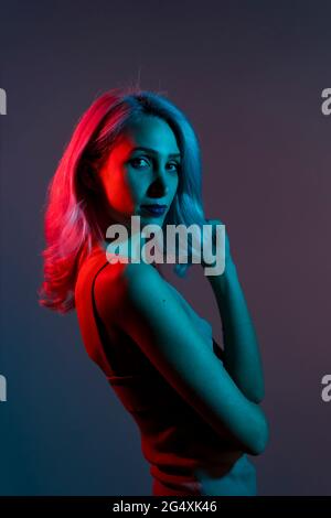 Schöne junge Frau, die über dunklem Hintergrund steht Stockfoto