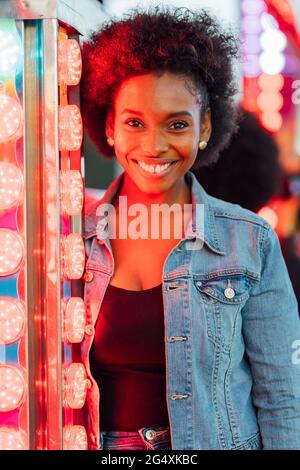Glückliche afrikanische Frau durch Beleuchtung Ausrüstung im Vergnügungspark Stockfoto