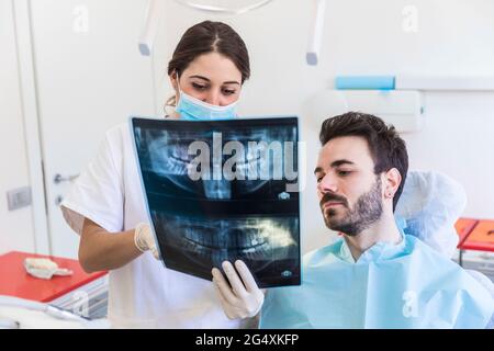 Zahnärztin, die der Patientin in der medizinischen Klinik Röntgenaufnahmen zeigt Stockfoto