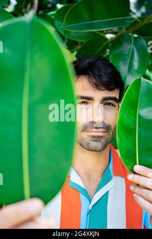 Hübscher junger Mann mit grünen Blättern Stockfoto