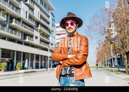 Mann mit Hut schaut weg, während er an sonnigen Tagen auf dem Fußweg steht Stockfoto