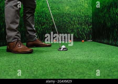 Geschäftsmann, der im Büro auf dem grünen Golfplatz Golf spielt Stockfoto
