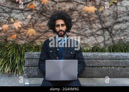 Geschäftsmann mit Laptop sitzen auf Bank Stockfoto