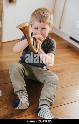 Junge, der zu Hause auf dem Boden sitzt und Tuba praktiziert Stockfoto