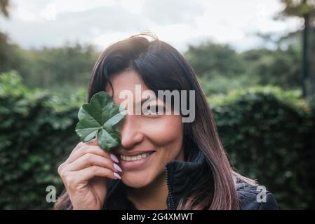 Lächelnde verspielte Frau mit Blatt bedeckenden Auge Stockfoto