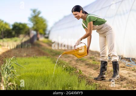 Junge Bäuerin gießt Pflanzen auf dem Bio-Bauernhof Stockfoto