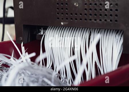 Zerkleinerung von Papieren, die aus der Maschine kommen. Aktenvernichtung von Dokumenten aus Sicherheitsgründen. Stockfoto