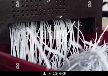 Zerkleinerung von Papieren, die aus der Maschine kommen. Aktenvernichtung von Dokumenten aus Sicherheitsgründen. Stockfoto
