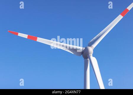 Windturbine, die gegen den klaren blauen Himmel steht Stockfoto
