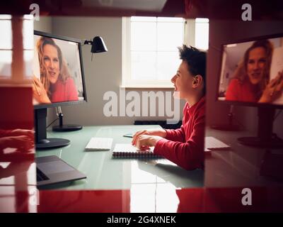 Lächelnder Junge, der während eines Videoanrufs zu Hause lernt Stockfoto