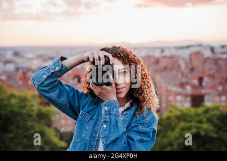 Lächelnde Fotografin, die im Park fotografiert Stockfoto