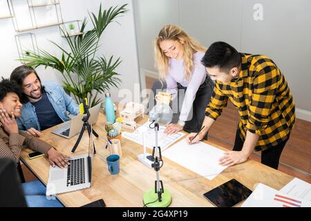 Architekten und Architektinnen diskutieren über Blaudruck mit Kollegen im Büro Stockfoto