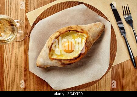 Adjarian khachapuri mit Weißwein auf Holzbrett Stockfoto