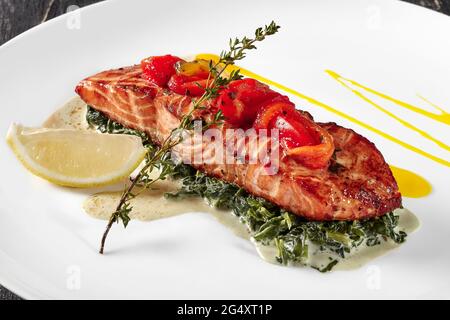 Gebackenes Lachssteak mit Spinat, geschmort in Creme und Zitrone Stockfoto