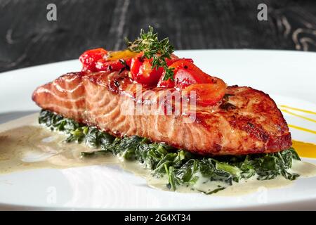 Gegrilltes Lachssteak mit geschmortem Spinat in Rahm Stockfoto