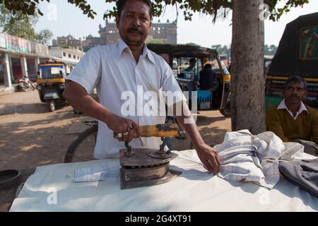 Der Dhobi oder indische Wäschemann (Waschen und Bügeln), der sein Geschäft im Freien in Orchha, Madhya Pradesh, betreibt. Stockfoto