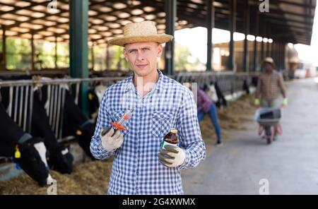 Landwirt mit Spritze und Medizin in den Händen auf dem Milchviehbetrieb Stockfoto