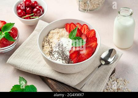 Haferbrei mit frischen Erdbeeren auf hellrosa Hintergrund. Stockfoto